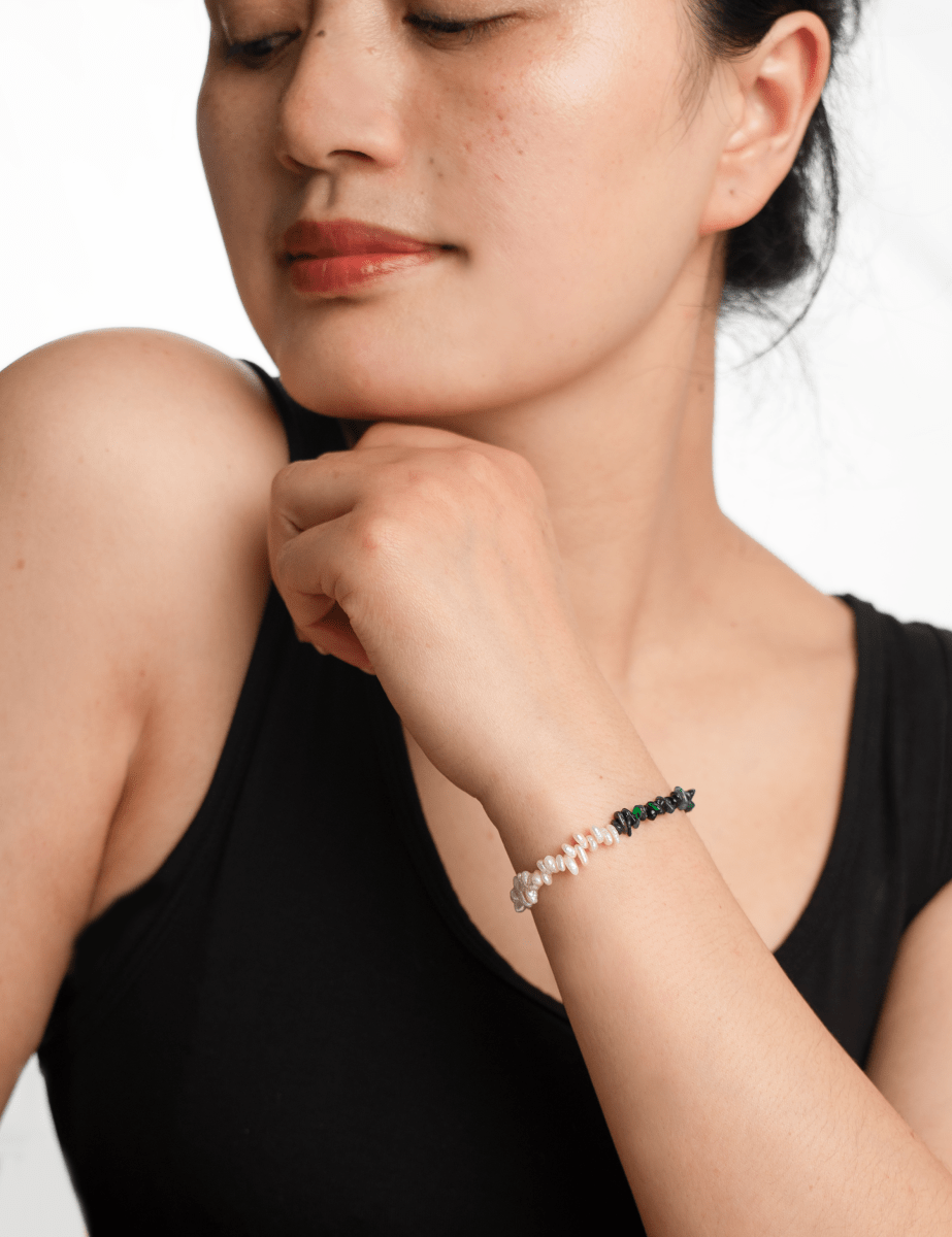 Woman wearing AURA DUO Black Opal Pearl Bracelet, showcasing its elegant design and mystical appeal.