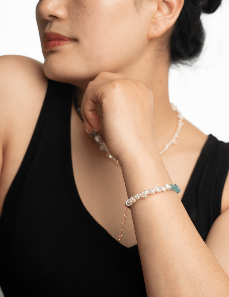 Close-up of a woman wearing the AURA DUO Apatite Pearl bracelet with spacer beads, showcasing its elegance and artistry.