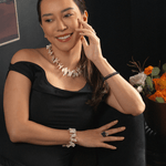 Woman wearing a Biwa-style stick pearl necklace and bracelet, smiling elegantly in a black off-shoulder dress.