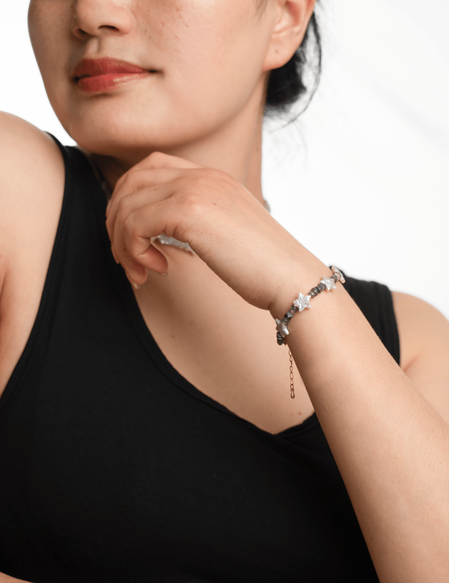 Woman wearing AURA DUO Gray Moonstone Star Pearl bracelet, showcasing its celestial charm and elegance.
