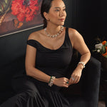 Woman in a black dress with Biwa-style pearl necklace, showcasing elegance and style, against a floral backdrop.