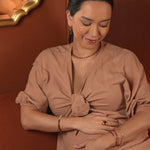 Woman wearing AURA DUO Orange Garnet Pearl Bracelet with elegant attire, showcasing jewelry against a warm background.