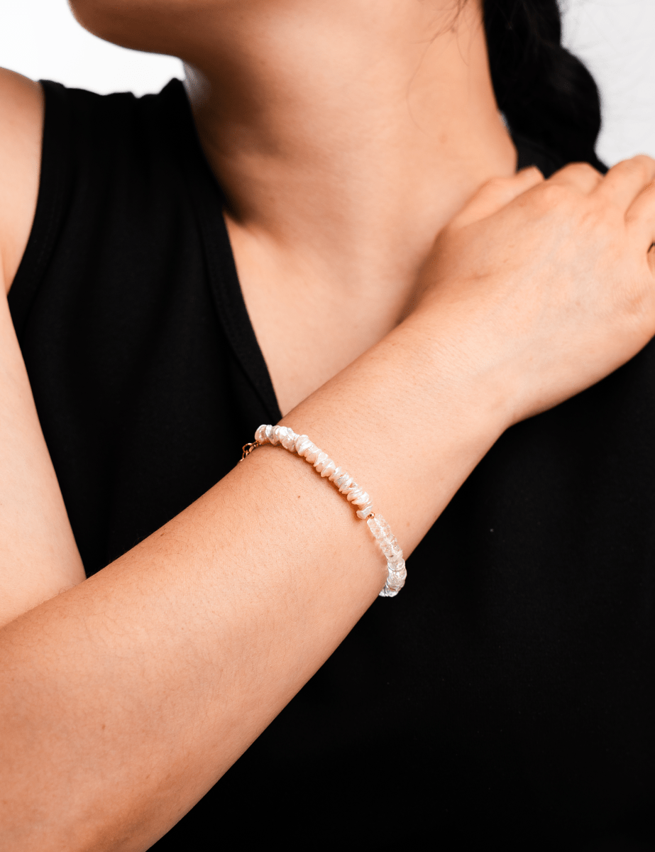 Close-up of a woman's wrist adorned with a delicate pearl and faceted bead bracelet, showcasing elegance and sophistication.