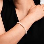 Close-up of a woman's wrist adorned with a delicate pearl and faceted bead bracelet, showcasing elegance and sophistication.