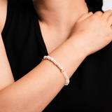 Close-up of a woman's wrist adorned with a delicate pearl and faceted bead bracelet, showcasing elegance and sophistication.