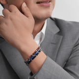 Man wearing Lapis Lazuli and Black Onyx bracelet, showcasing elegance and style in a grey suit.
