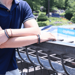 Man wearing a black onyx bracelet with sterling silver zodiac spacer beads, enjoying a sunny day outdoors.