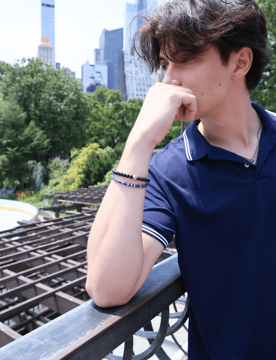 Man wearing a black onyx and sterling silver zodiac spacer bracelet outdoors, showcasing a stylish and grounding accessory.