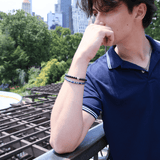Man wearing a black onyx and sterling silver zodiac spacer bracelet outdoors, showcasing a stylish and grounding accessory.