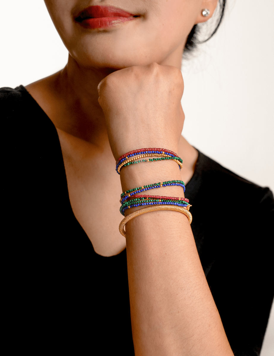Woman wearing colorful bracelets stacked on wrist, showcasing vibrant designs and textures.