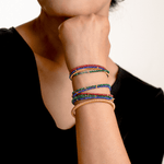 Woman wearing colorful bracelets stacked on wrist, showcasing vibrant designs and textures.