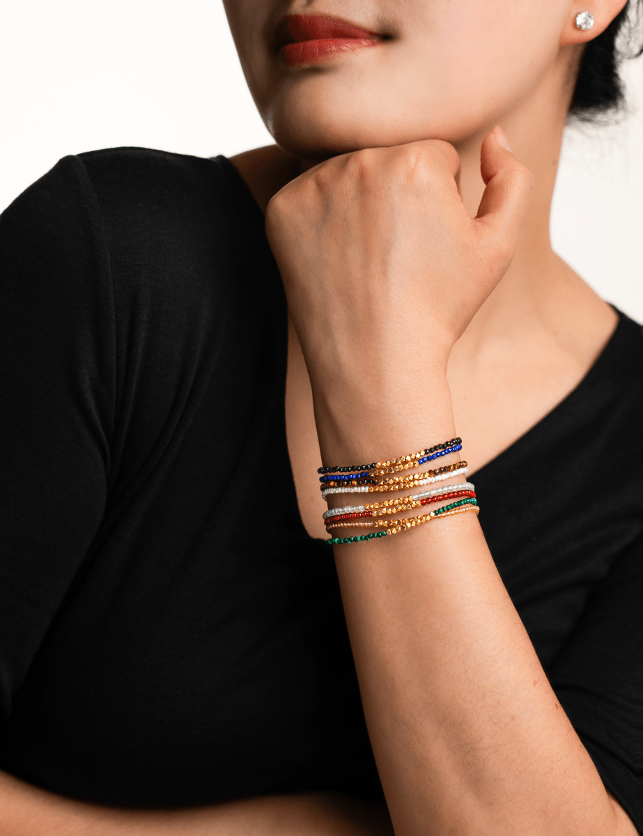 Model showcasing layered dainty bracelets, highlighting vibrant colors and intricate spacer beads.