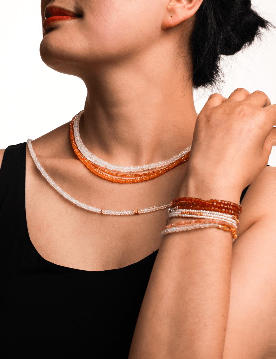 Model wearing a vibrant Orange Garnet necklace and bracelets, showcasing the 4mm faceted beads for personal growth and creativity.