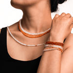 Model wearing a vibrant Orange Garnet necklace and bracelets, showcasing the 4mm faceted beads for personal growth and creativity.