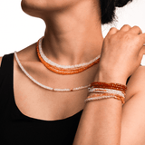 Model wearing a vibrant Orange Garnet necklace and bracelets, showcasing the 4mm faceted beads for personal growth and creativity.