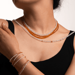Model wearing layered necklace and bracelets made of faceted moonstone and silver spacer beads, showcasing elegance and style.