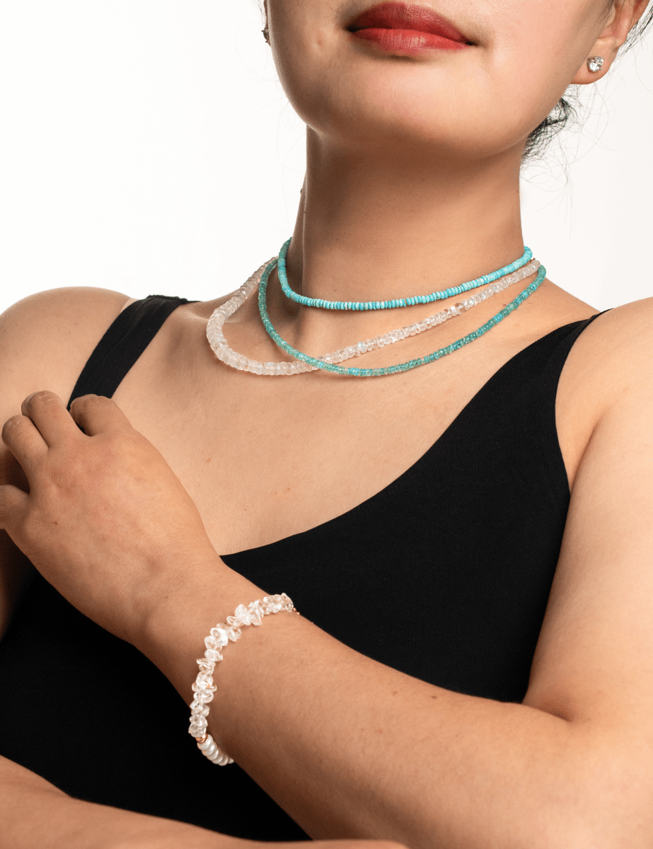 Model wearing turquoise faceted dainty necklace and a bracelet, showcasing elegant jewelry and a sense of style.