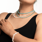 Model wearing turquoise faceted dainty necklace and a bracelet, showcasing elegant jewelry and a sense of style.