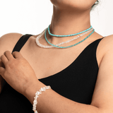Model wearing turquoise faceted dainty necklace and a bracelet, showcasing elegant jewelry and a sense of style.
