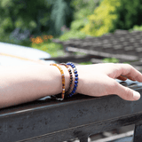 Hand wearing a lapis lazuli bracelet with sterling silver zodiac spacer beads, showcasing the bracelet's beautiful colors.