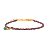 Dainty garnet bracelet with turquoise charm and sterling silver clasp, symbolizing love and protection.