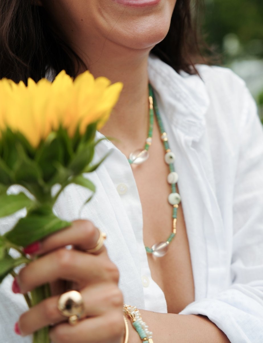 Woman wearing MIRA Green Opal, Pearl & Clear Quartz choker necklace, holding yellow flowers.
