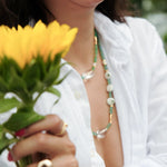 Woman wearing MIRA Green Opal, Pearl & Clear Quartz choker necklace, holding yellow flowers.