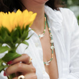 Woman wearing MIRA Green Opal, Pearl & Clear Quartz choker necklace, holding yellow flowers.