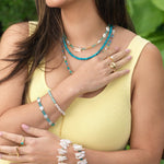 Woman wearing layered blue apatite and pearl jewelry, showcasing vibrant bracelets and necklaces for a chic summer look.