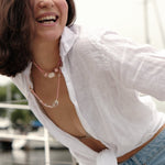 Smiling woman in white shirt wearing MIRA Pink Opal & Clear Quartz beaded choker necklace on a boat.