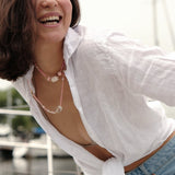 Smiling woman in white shirt wearing MIRA Pink Opal & Clear Quartz beaded choker necklace on a boat.