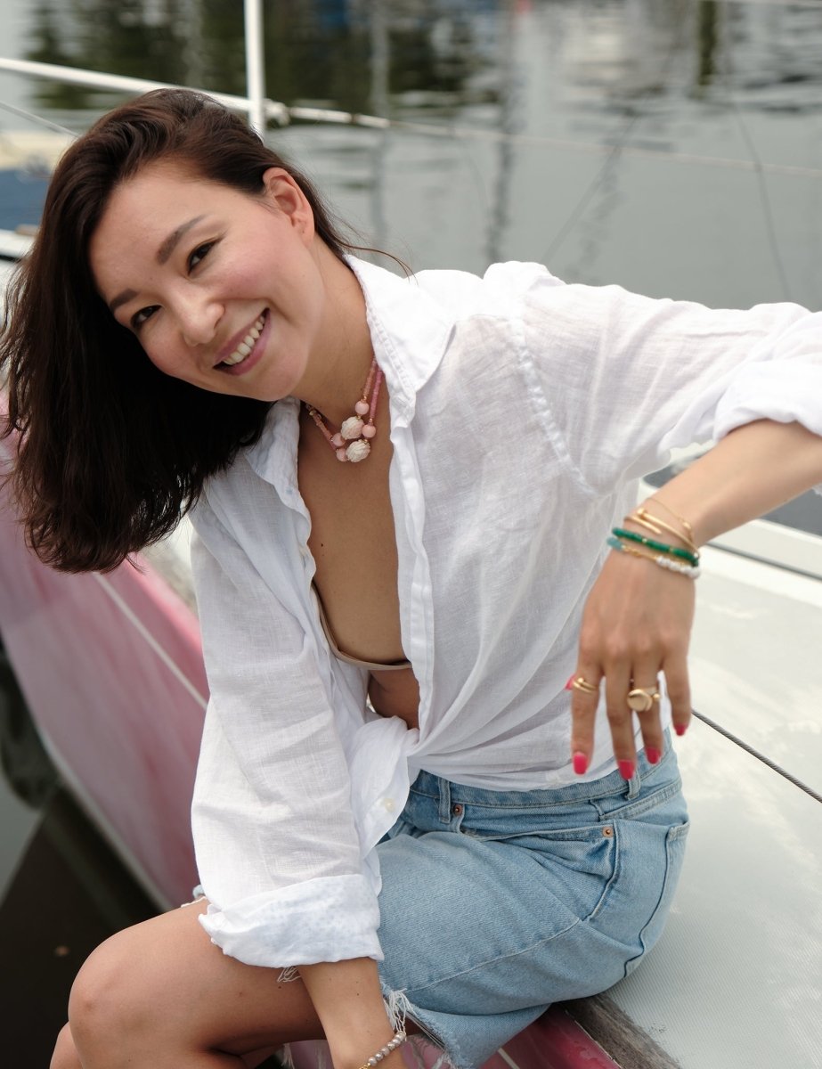 Woman wearing a MIRA Pink Opal & Clear Quartz beaded choker necklace, smiling on a boat.