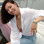 Woman wearing a MIRA Pink Opal & Clear Quartz beaded choker necklace, smiling on a boat.