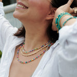 Model wearing MIRA Rainbow Opal & Clear Quartz beaded choker necklace, showcasing vibrant colors and gold-plated accents.