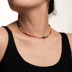Woman wearing a colorful Rainbow Sapphire necklace, showcasing vibrant faceted beads for positivity and emotional healing.