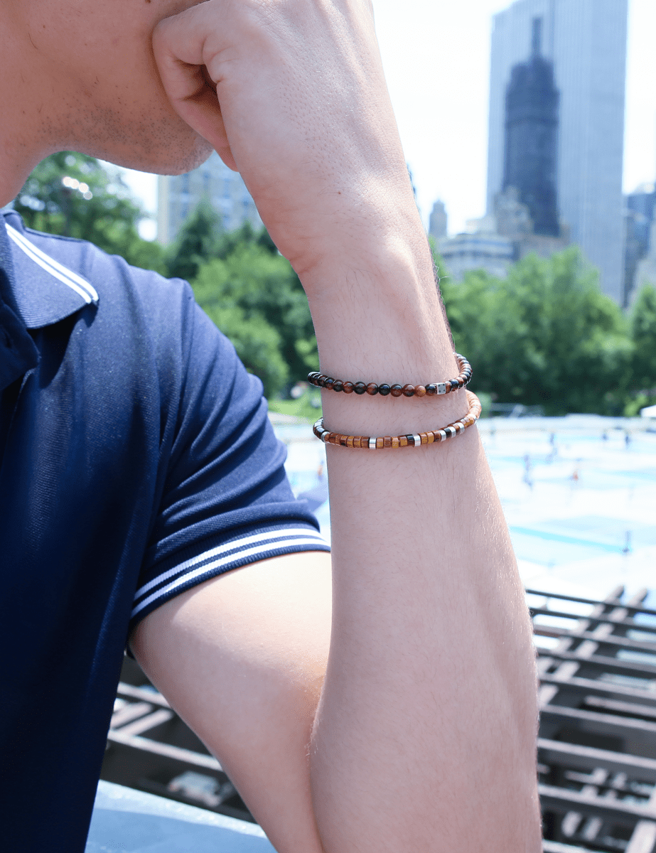 Man wearing a red tiger eye bracelet with silver dice spacer beads, showcasing style in an urban setting.