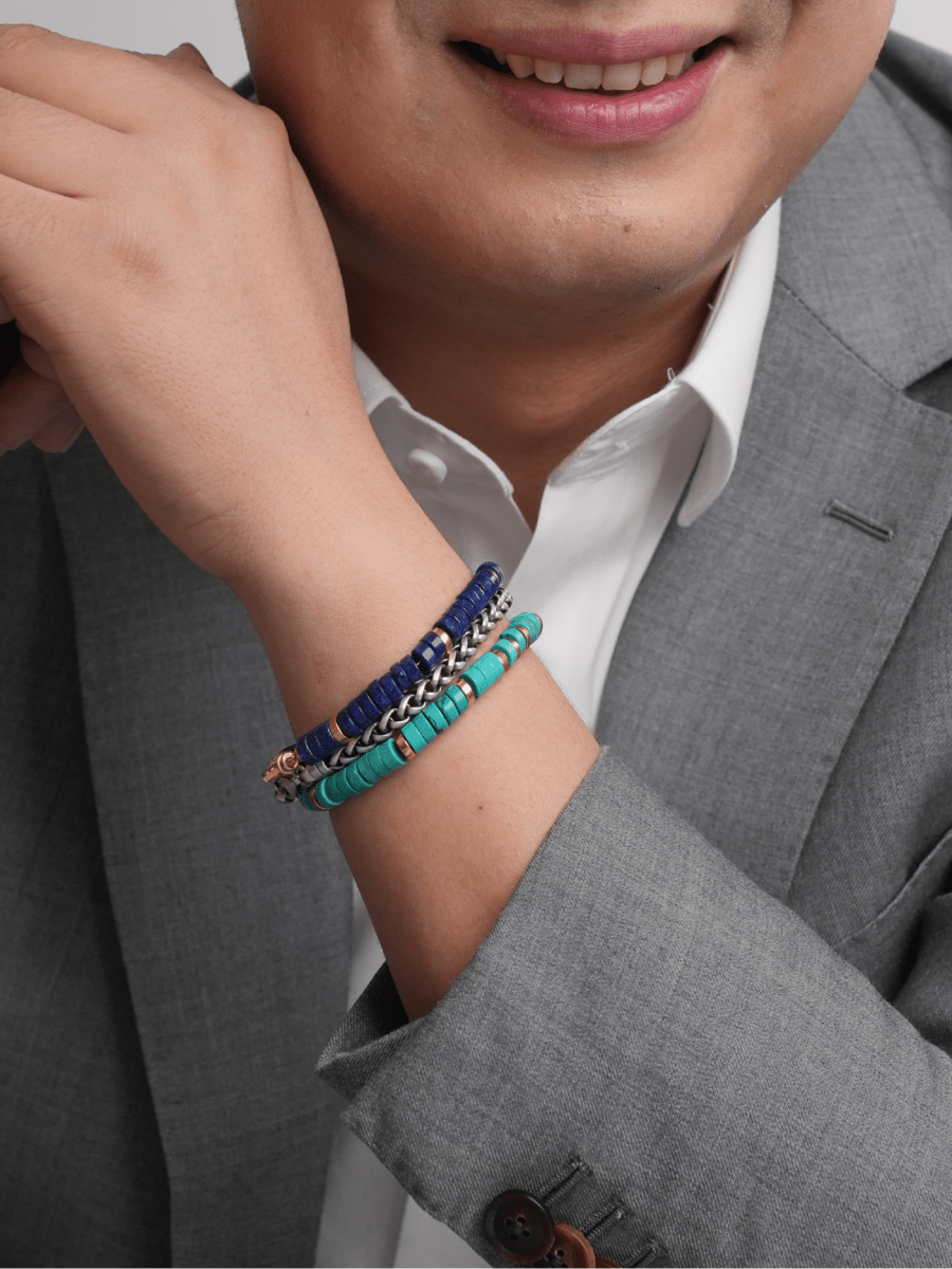Man wearing a stylish turquoise and gold-plated sterling silver bracelet with a gray suit, showcasing elegance and sophistication.