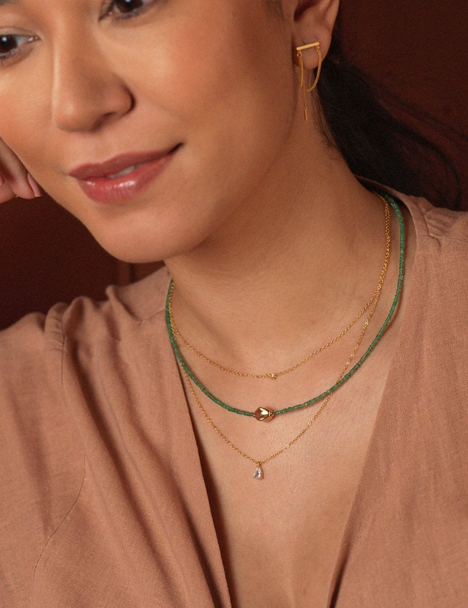 Model showcasing SHANGHAI Emerald Beaded Necklace in 18K gold layered with chic jewelry.