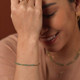 Model wearing a SHANGHAI Tsavorite tube necklace and bracelet in 18K gold, showcasing a minimalist yet vibrant style.