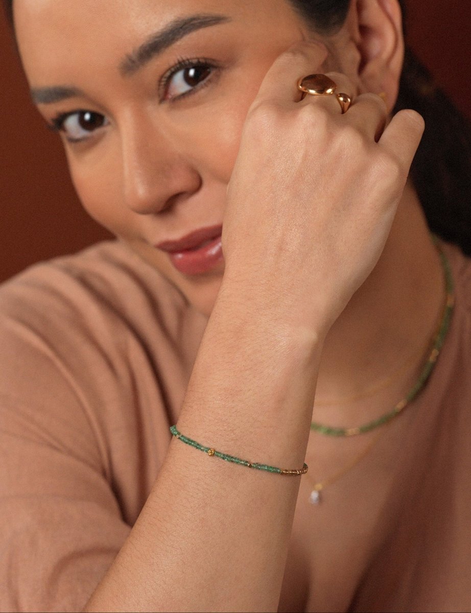 Woman wearing SHANGHAI Emerald Spring Glimmer Beaded Bracelet with 18K Gold accents, showcasing elegance and beauty.