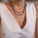 Elegant layered necklace featuring sapphire and blue topaz beads worn by a model in a white top.