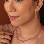 Model showcasing a layered necklace with pink sapphires and citrine gemstones, paired with elegant gold jewelry.