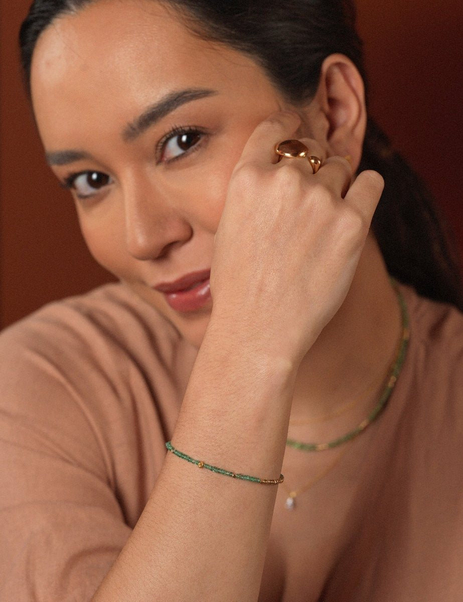 Model wearing vibrant tsavorite jewelry with 18K gold accents, showcasing a minimalist and elegant style.