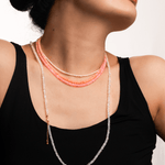 Woman wearing a faceted dainty necklace featuring orange opal beads, radiating warmth and confidence.