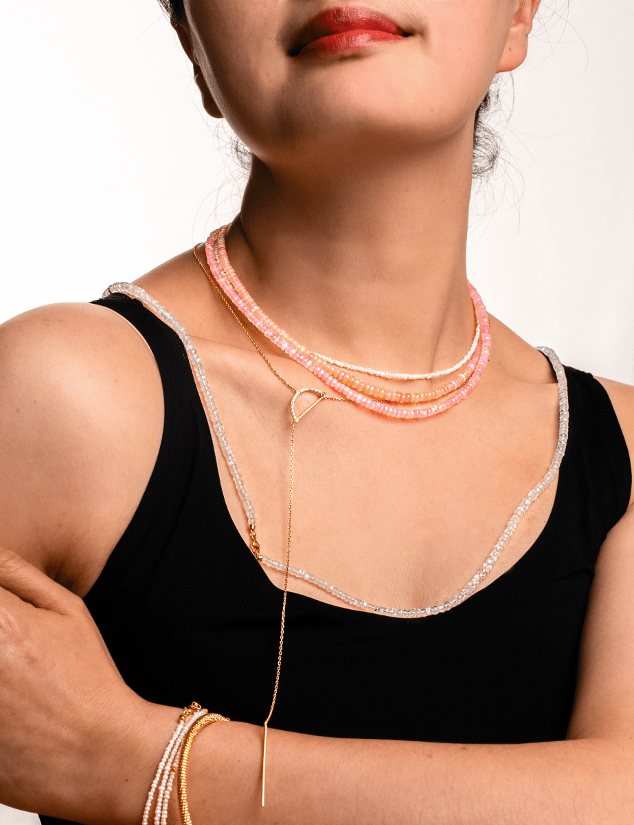 Stylish woman wearing a dainty necklace layered with pink and silver strands, showcasing elegant jewelry.