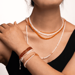 Model wearing multiple strands of Success Orange Sapphire and crystal necklaces and bracelets, showcasing elegance and style.