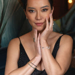 Woman wearing elegant jewelry, featuring silver bracelets, showcasing a confident pose in a stylish setting.