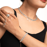 Woman wearing a multi-layer aquamarine bracelet, silver jewelry, and a pendant neckpiece, showcasing elegant minimalist style.