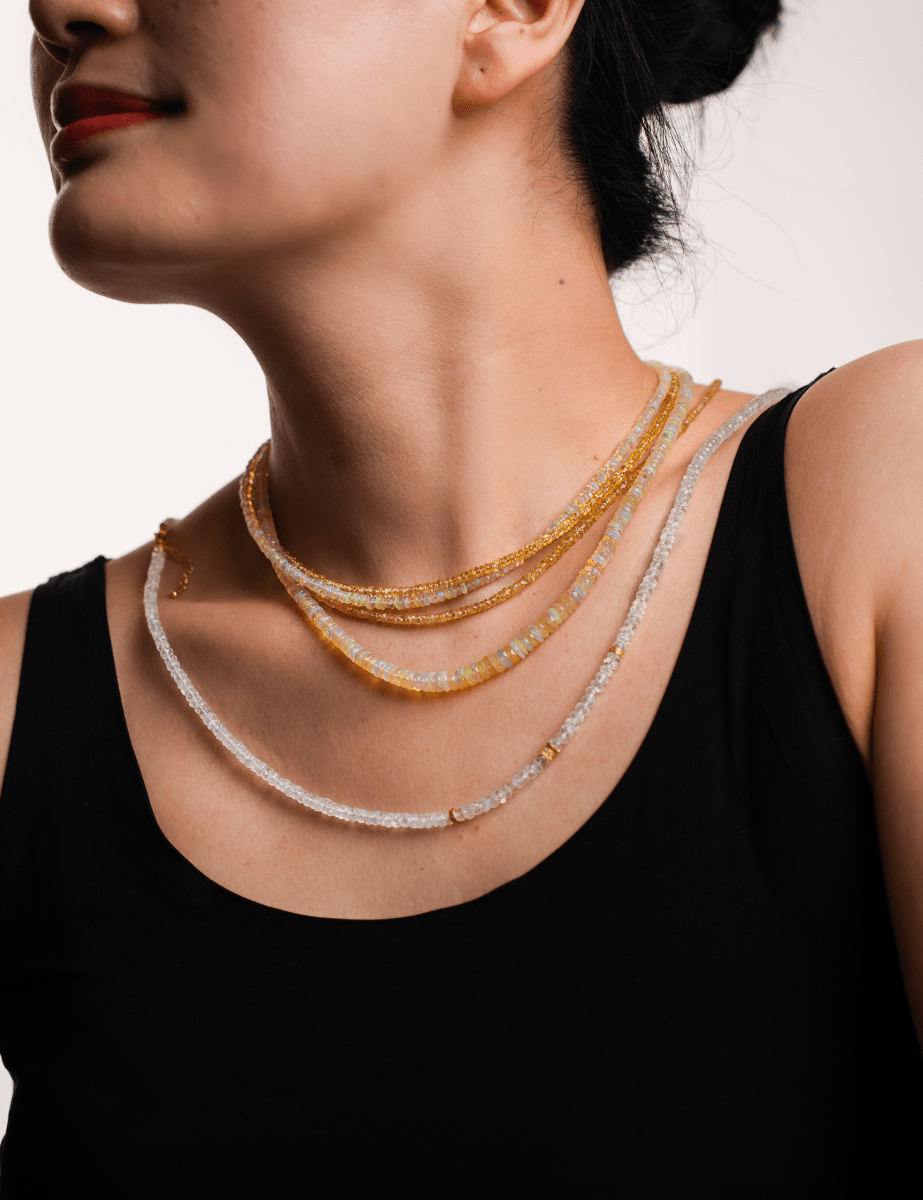 Woman wearing a layered Wealth Yellow Sapphire necklace, showcasing 4mm faceted beads that symbolize success and prosperity.