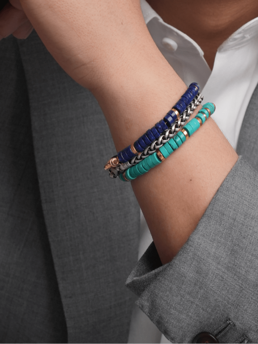 Men's wrist adorned with colorful Lapis Lazuli and turquoise bracelets, showcasing style and elegance.